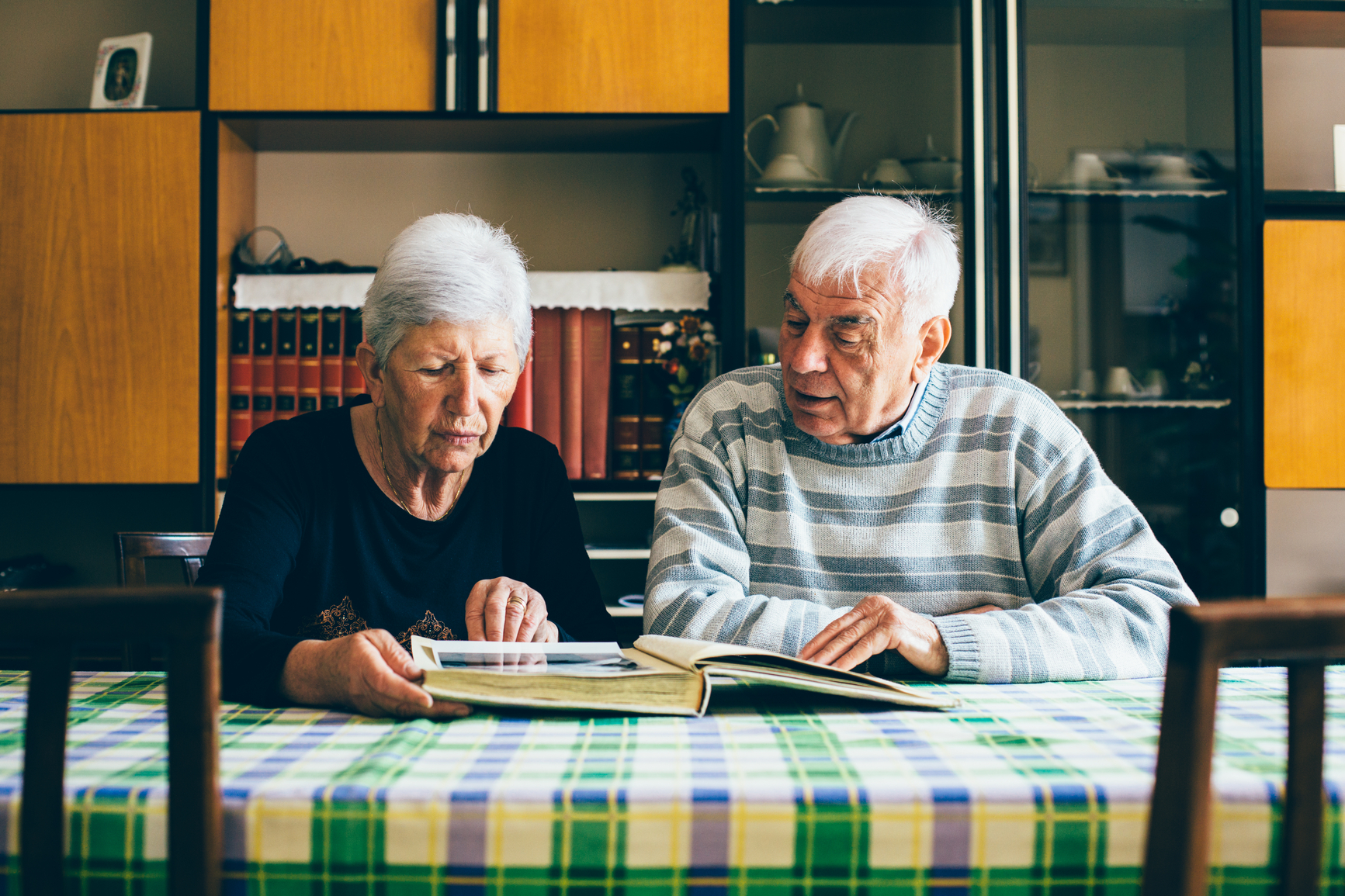 Older couple sat at table looking through photo album