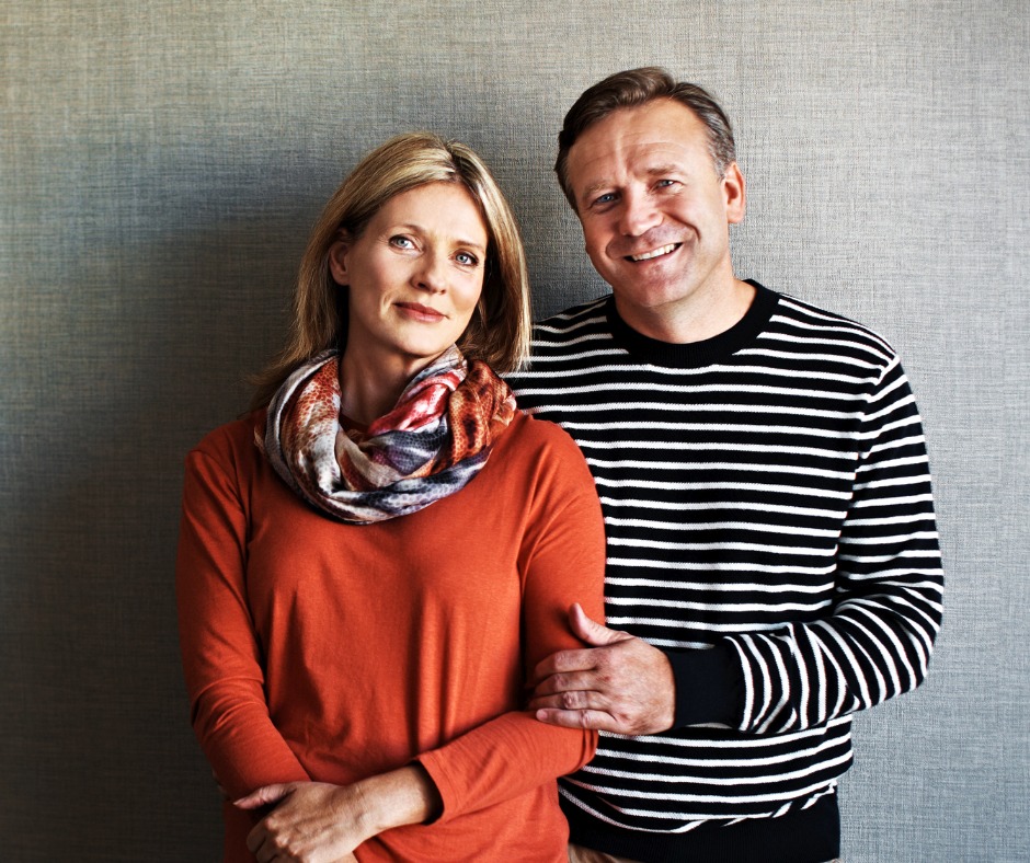 A woman in an orange jumper and a man in a stripey black and white jumper
