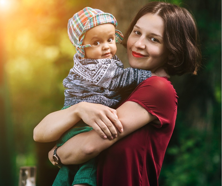 Woman smiling at camera and holding baby